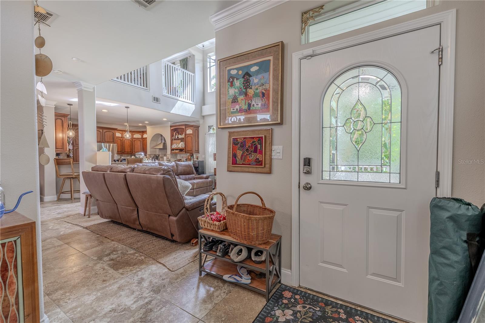 The front entry showcases a beautifully detailed glass-paneled door with an arched leaded-glass window that fills the foyer with soft, natural light while maintaining privacy.