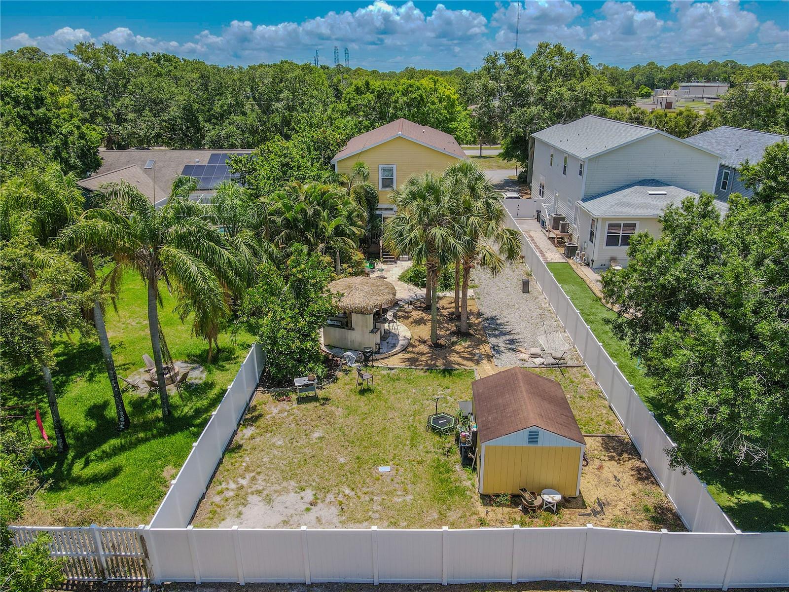 BackyardEscape to your private tropical retreat! This fully fenced backyard features mature palms, lush landscaping, a tiki-style outdoor bar and grilling area, a paver patio with lounge seating, a hammock zone, and a detached storage shed. Ideal for entertaining or relaxing in your own slice of paradise.