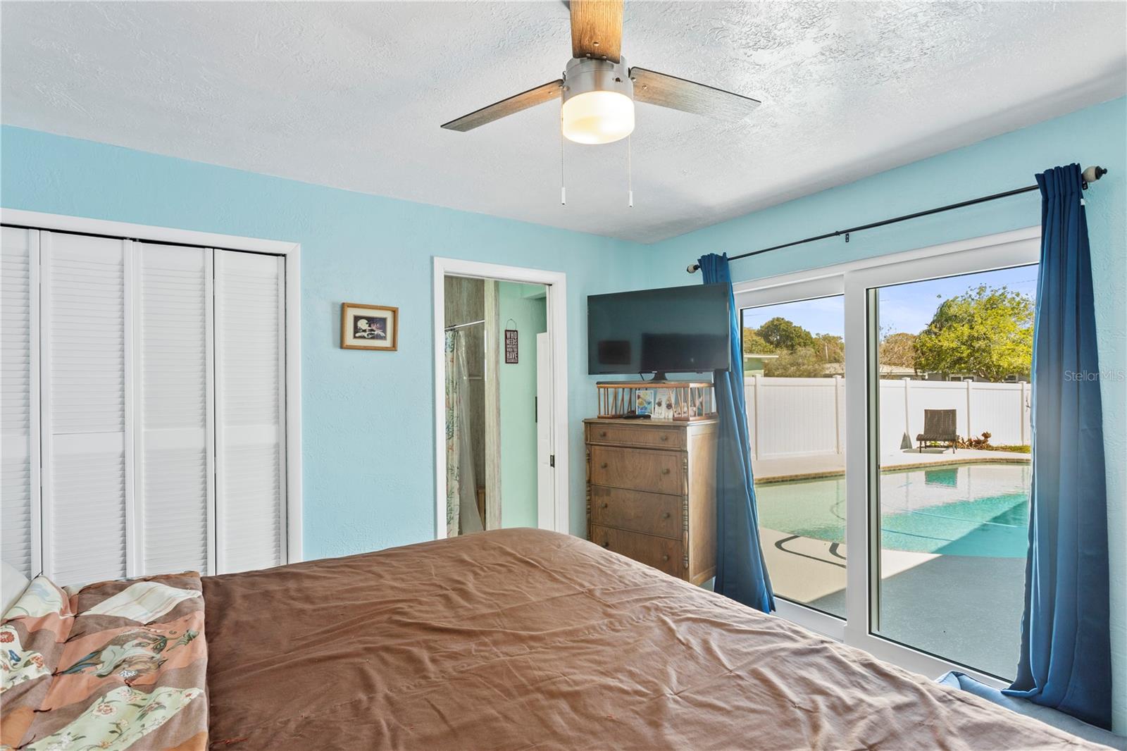 Primary bedroom suite overlooking the pool area features a walk-in closet and en suite shower/bath.