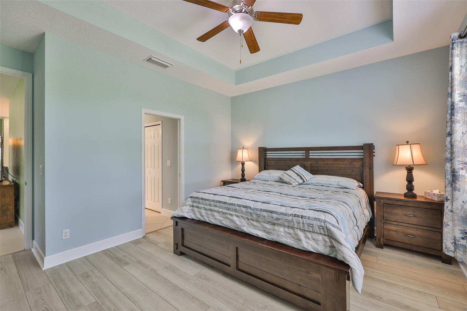 Primary owners suite is just off of the main living area.  Soft paint tones and stunning plank flooring accent this beautiful room.