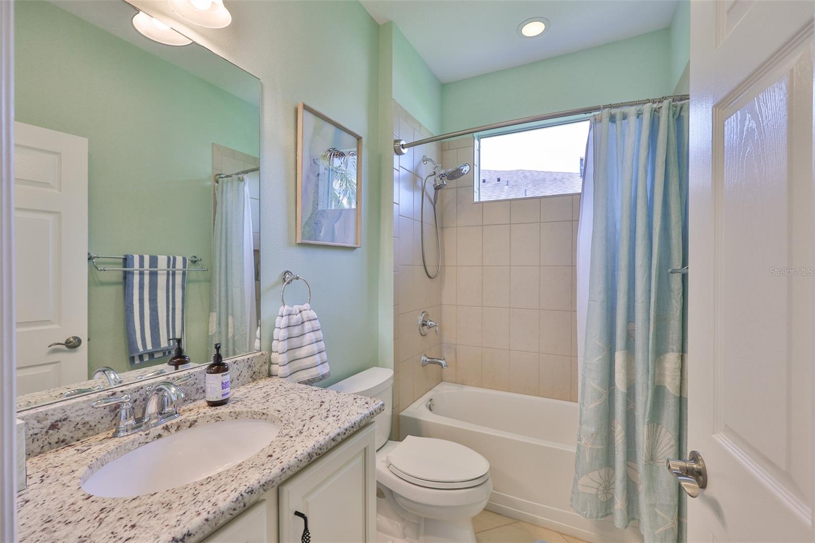 Guest bath is bright with natural light and granite countertops and cabinetry that matches the rest of the home.