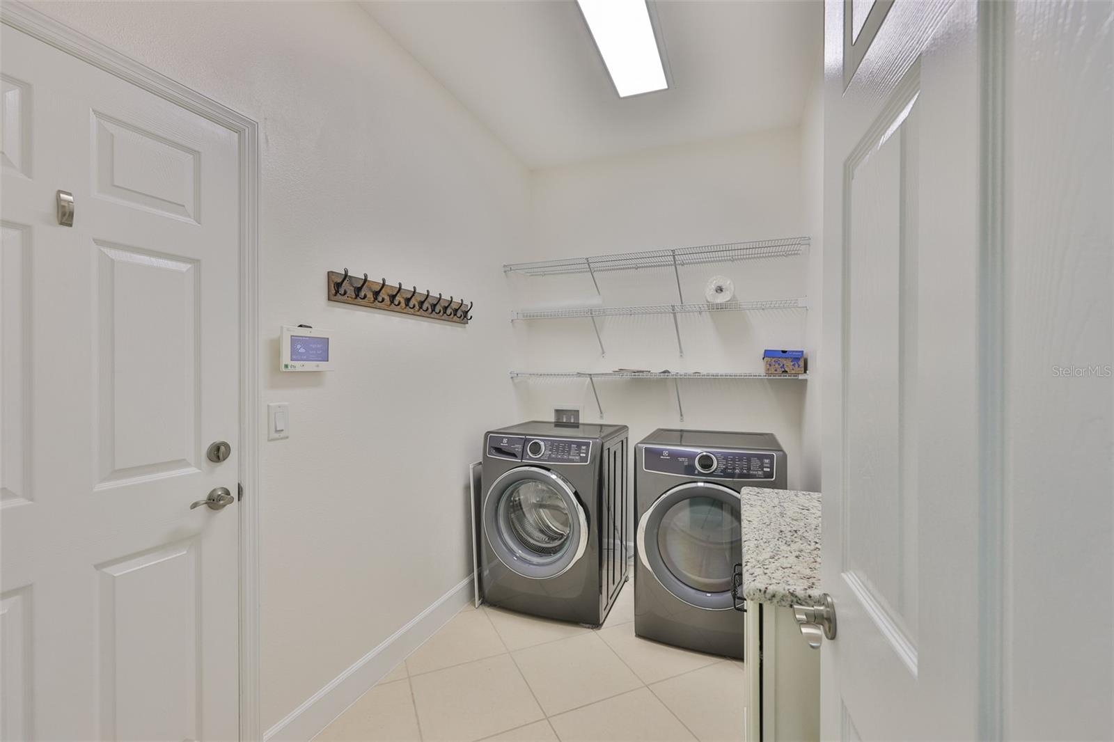 Laundry room is bright and spacious with matching cabinetry, granite and shelving.