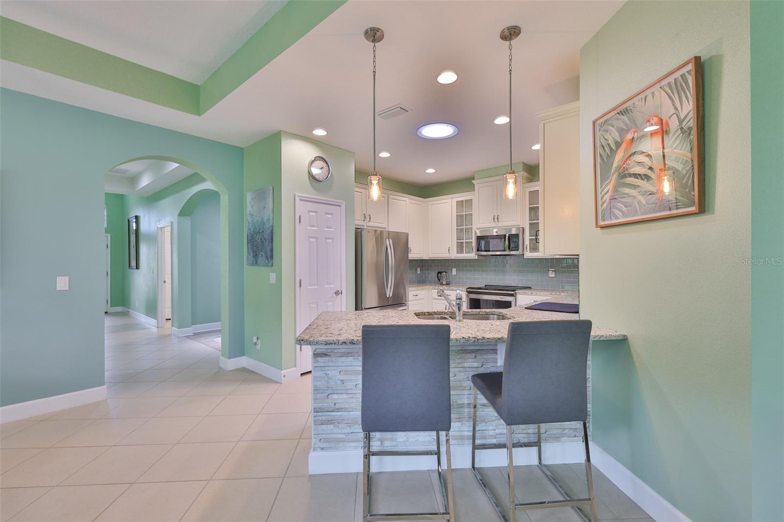 The hallway flows right into the main living area.  Paint tones are soft, Floridian tones with splashes of accent colors and bright white.  Notice the solar tube in the kitchen (large light in the ceiling).