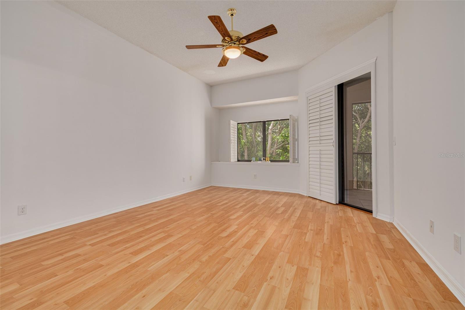 Primary bedroom with slider to lanai on the right. Wide window for beautiful natural light and a view of the trees!