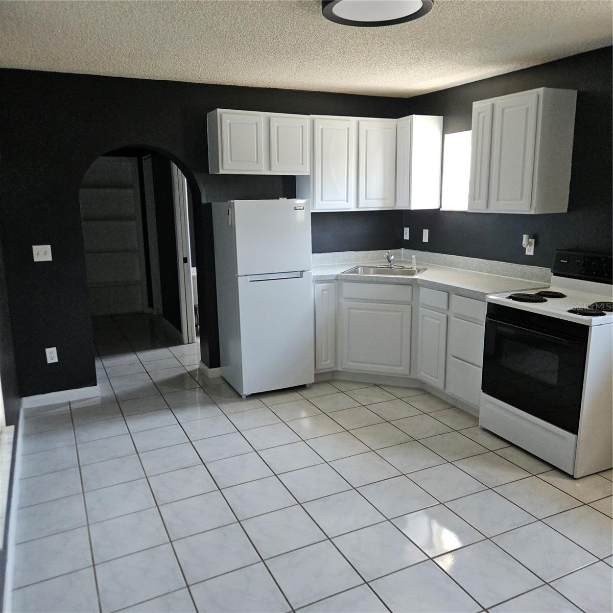 Apartment Kitchen with Stove and Refrigerator.  Plenty of Room for a dining table and chairs.