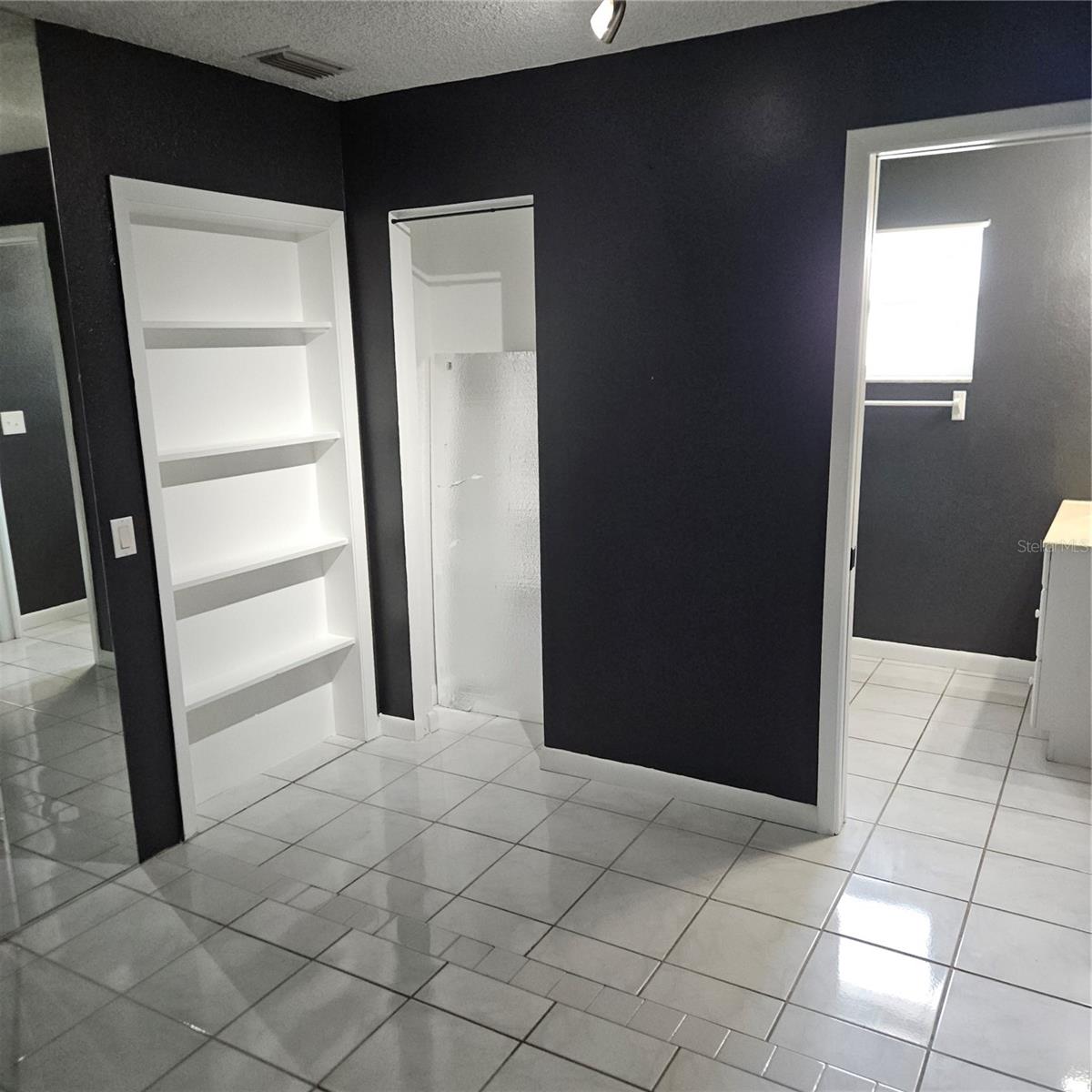 Apartment Living Room with built in shelving and a closet.  (other sound proof panel shown in closet) and doorway to bathroom