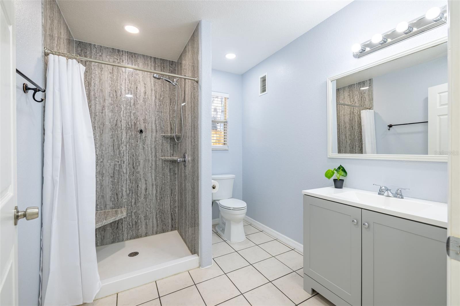 The primary bathroom is spacious and features a large walk-in shower with a built-in seat for added comfort and convenience.