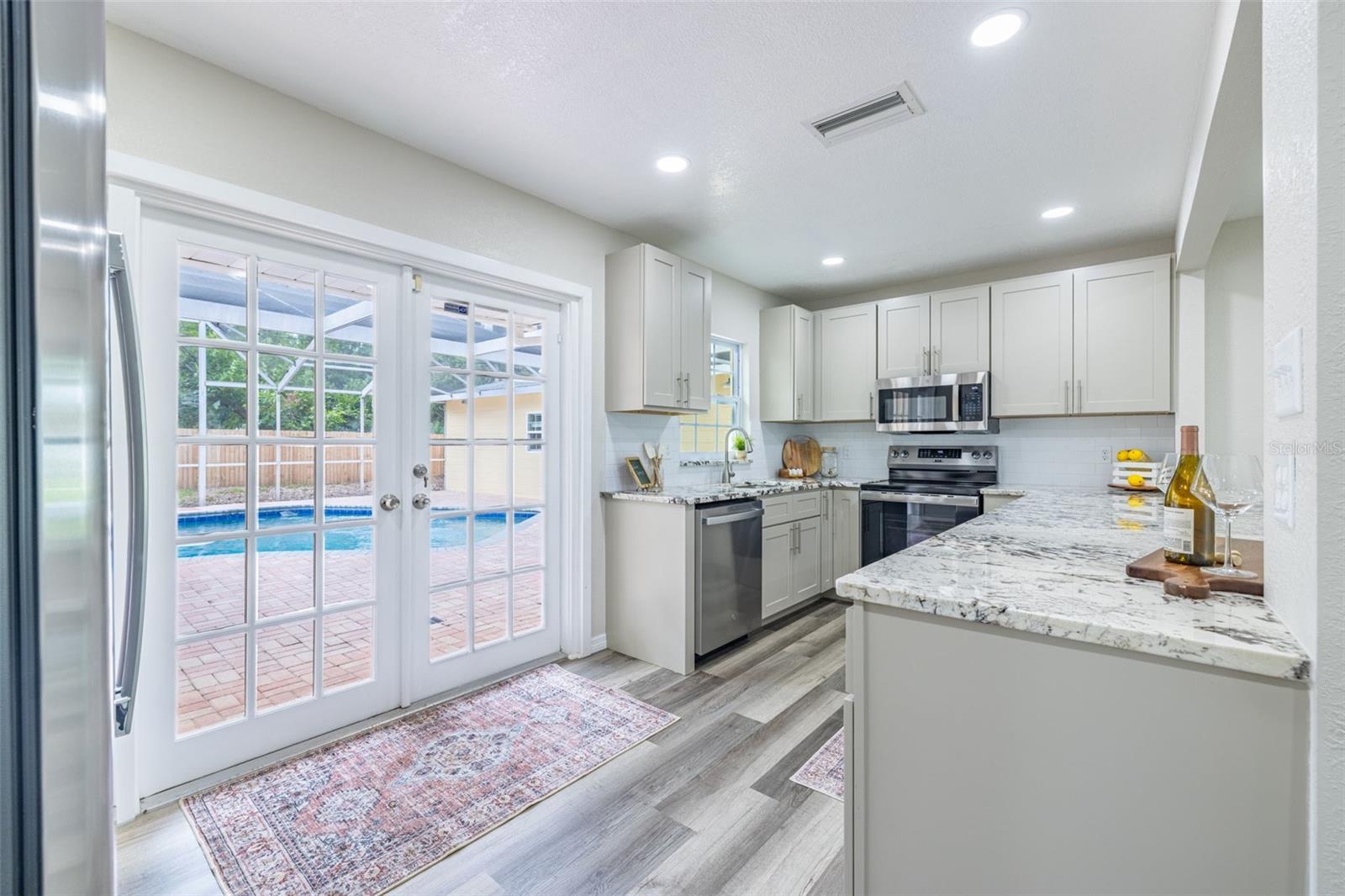 French doors off the kitchen open to a beautiful outdoor pool area, perfect for entertaining or relaxing in your private backyard oasis.