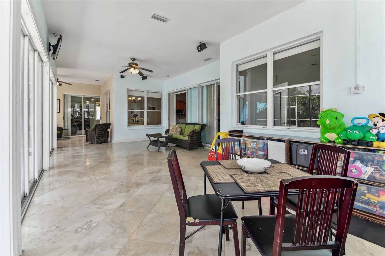 Bright Florida room with travertine flooring and panoramic windows overlooking the pool and backyard — perfect for relaxing year-round.