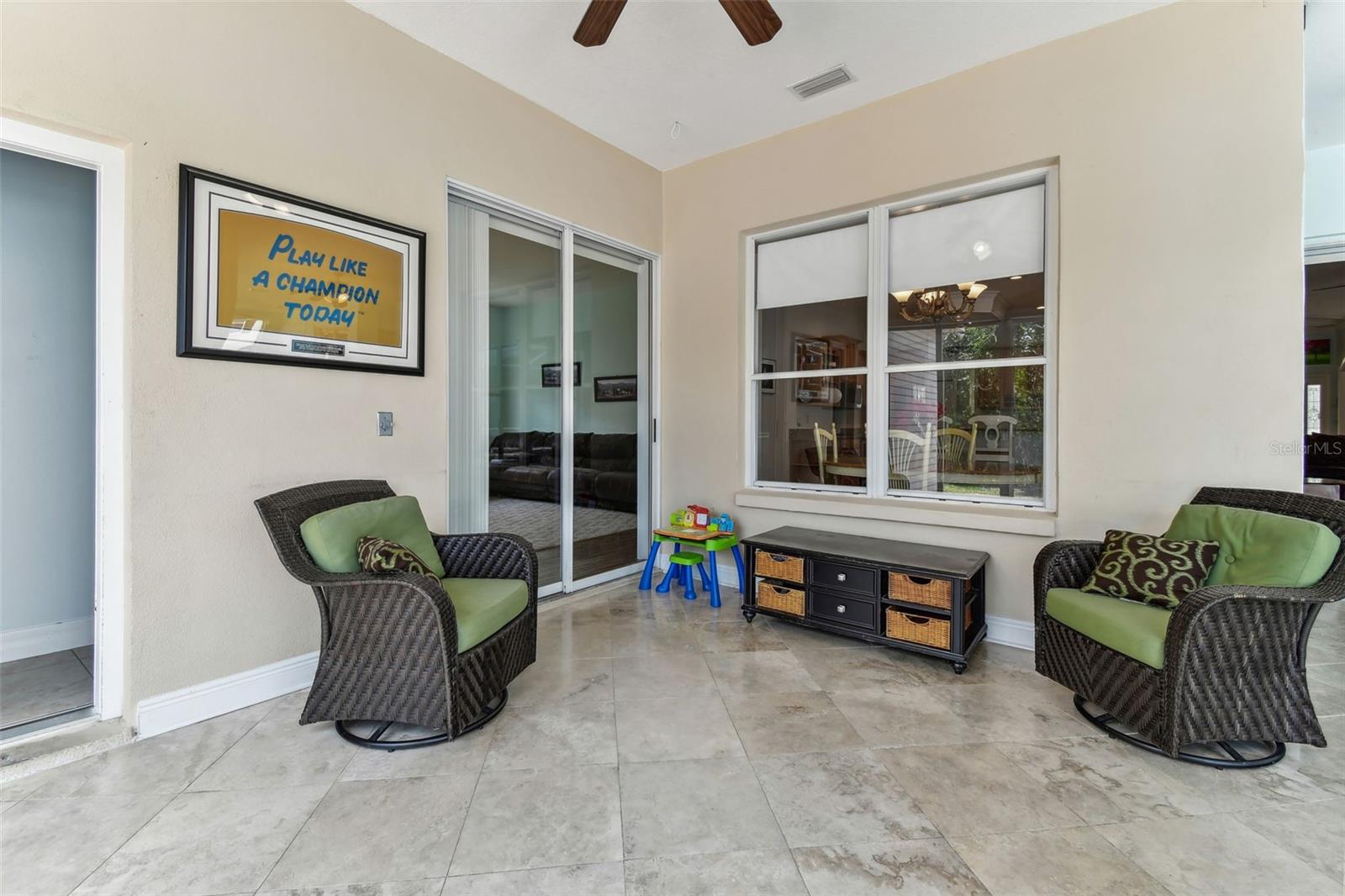 Bright Florida room with travertine flooring and panoramic windows overlooking the pool and backyard — perfect for relaxing year-round.