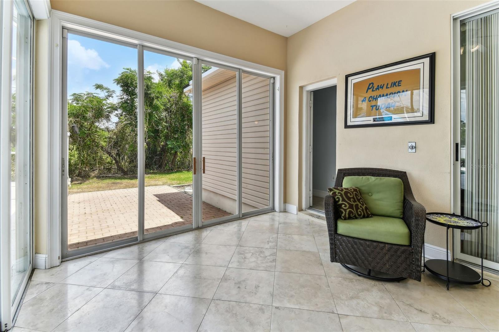 Bright Florida room with travertine flooring and panoramic windows overlooking the pool and backyard — perfect for relaxing year-round.