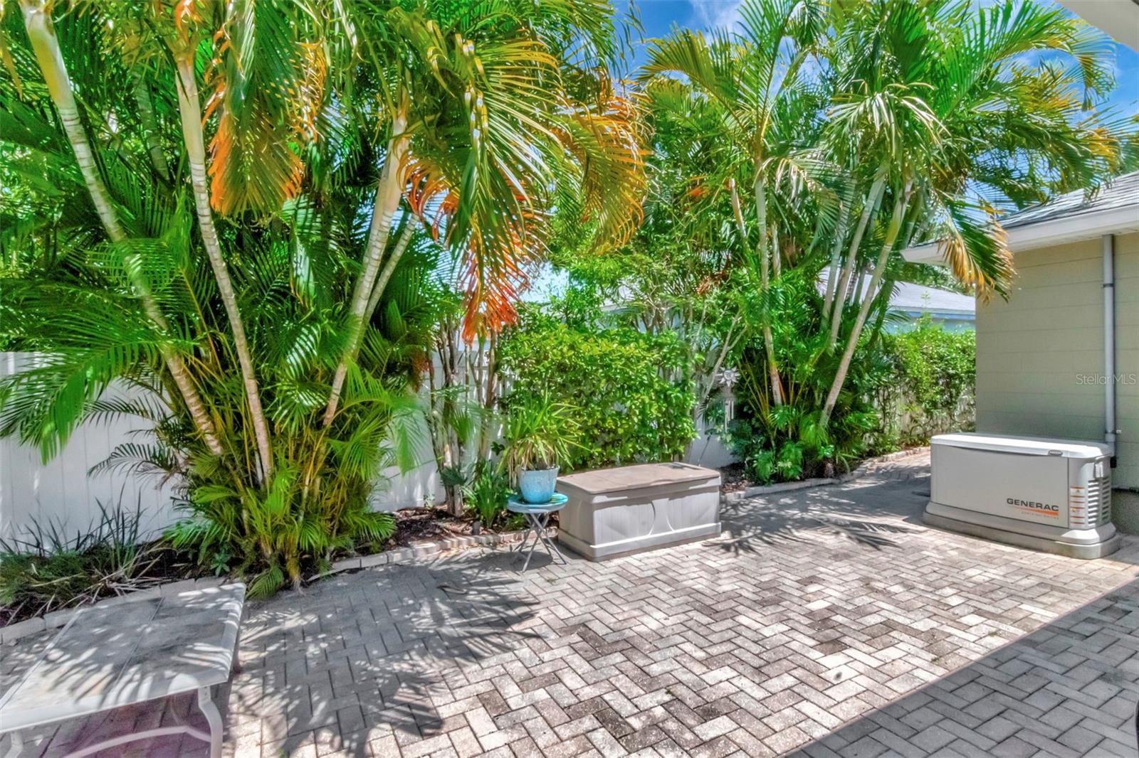 Lush landscaping graces low maintenance yard with lighting, sprinkler system, and paver patio.