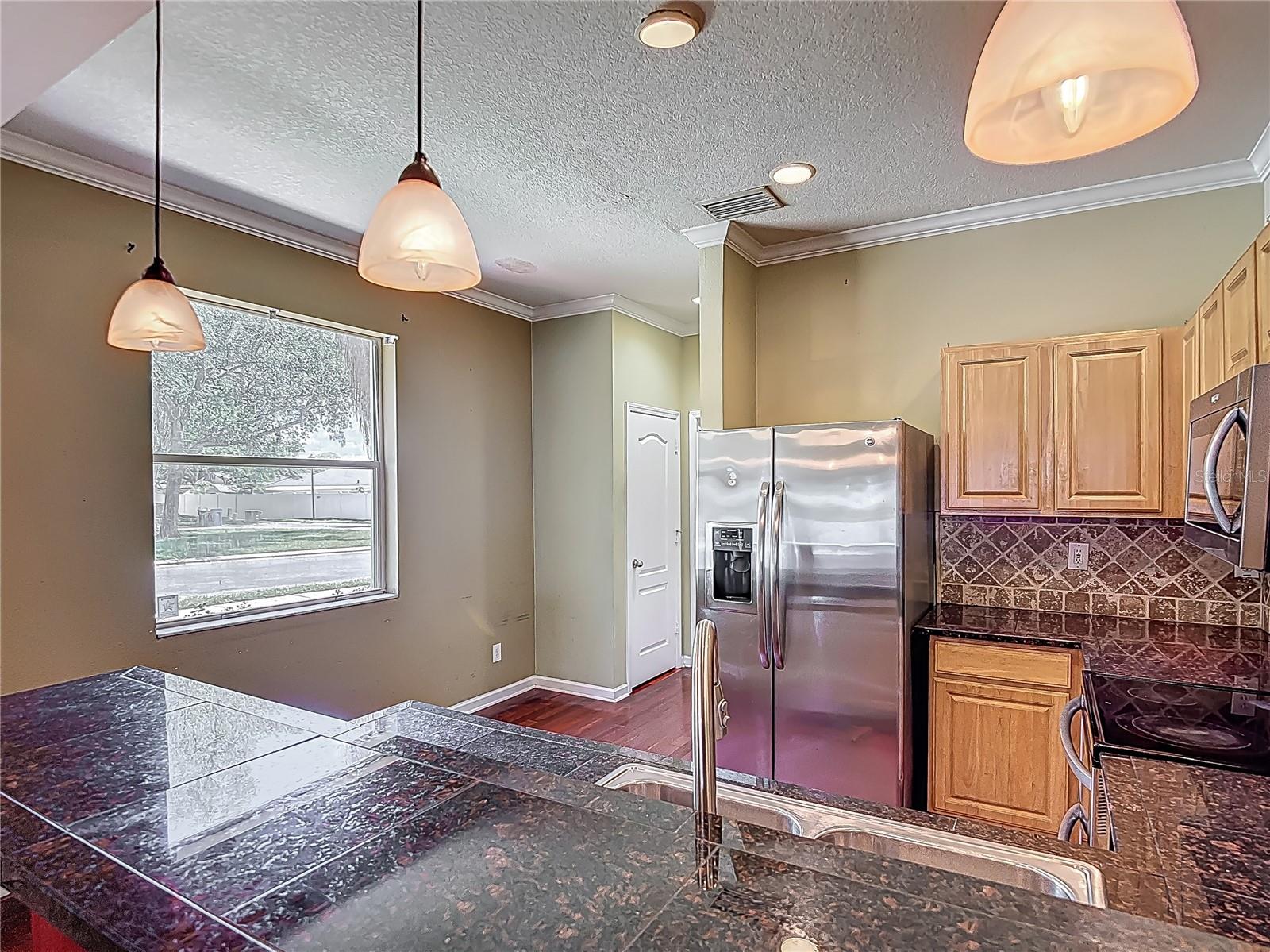 Kitchen, small eating space at the window. Door in view is pantry. Next to pantry is powder bath, across from pantry is door to garage.