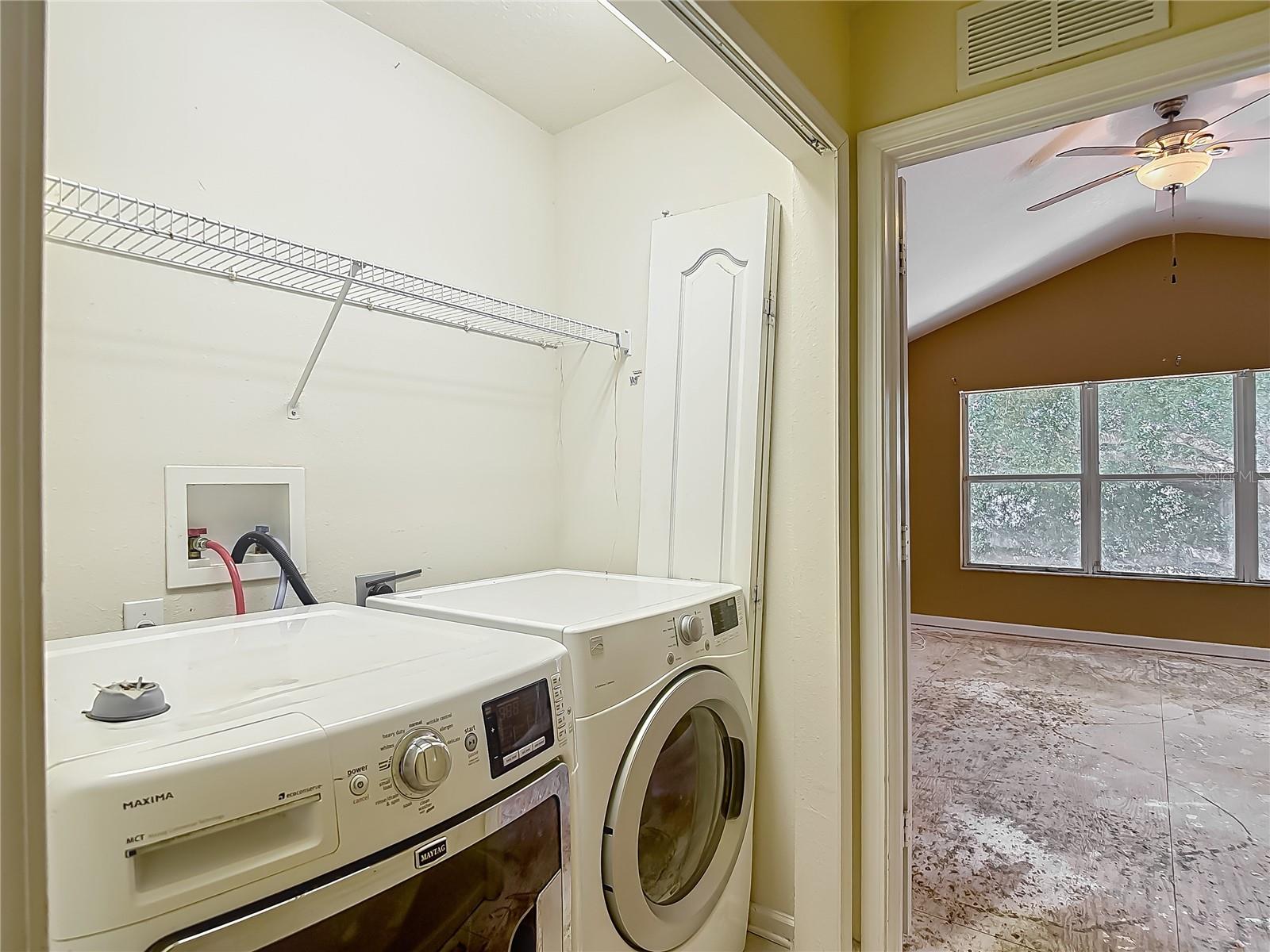 Laundry closet with full size front load washer & dryer. Primary bedroom just beyond.