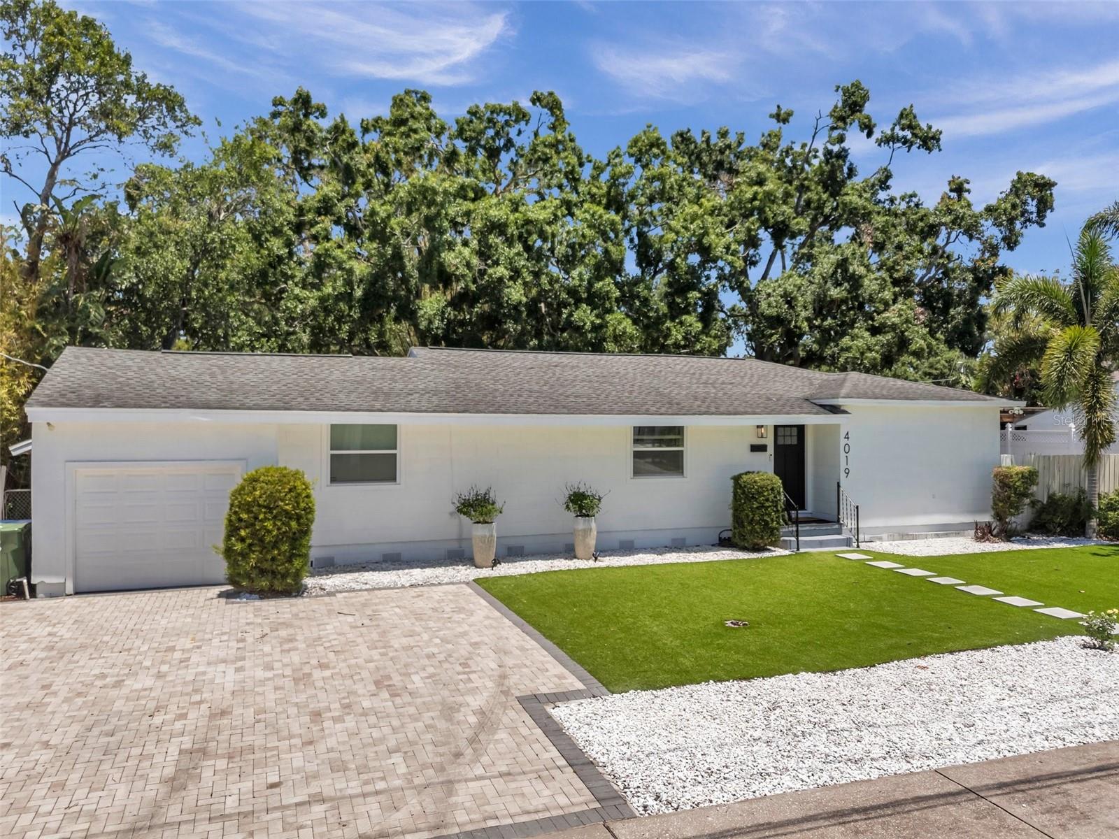 Pavered driveway with artificial turf and brand new marble rocks outlining the front exterior