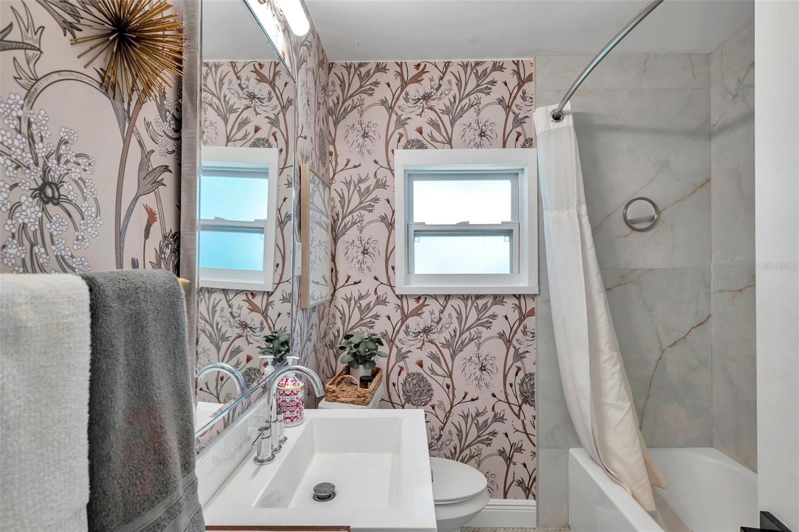 Updated bathroom with all new fixtures, new floor to ceiling tiles, new vanity and chic wall paper
