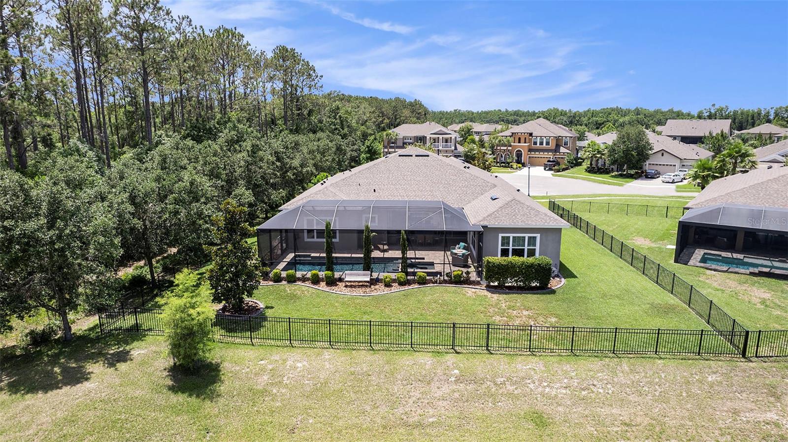 Backyard view of fenced yard and screened in pool and patio