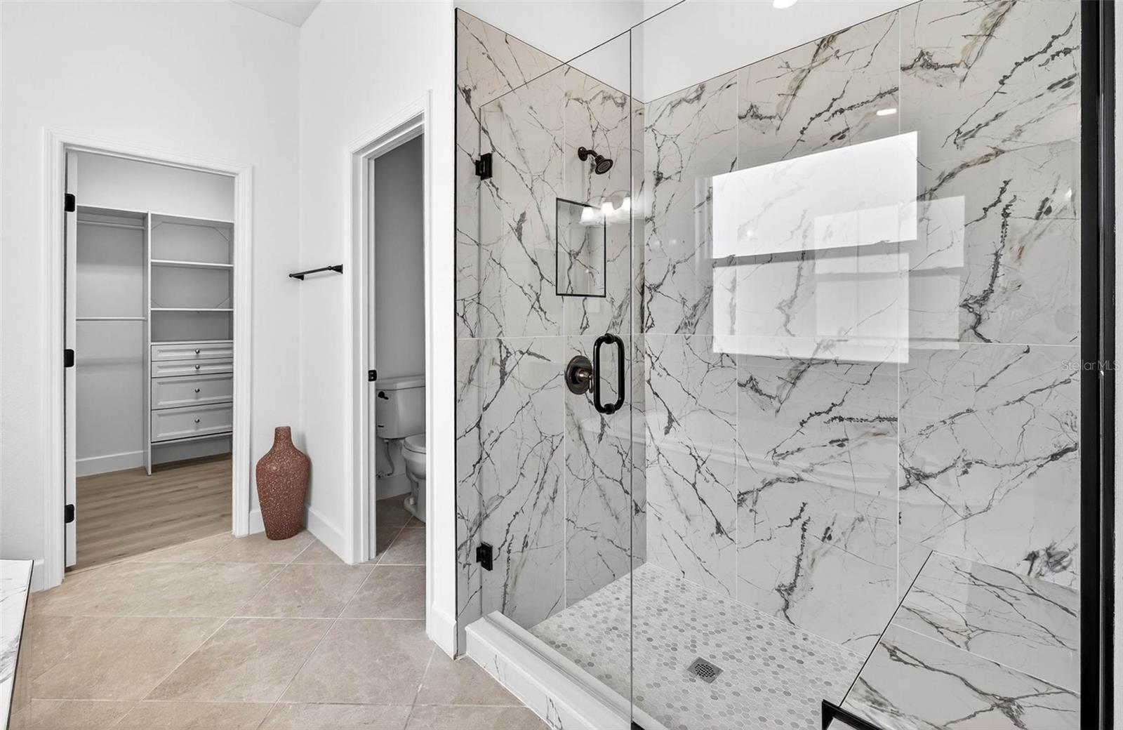 Walk in shower to the primary with view of water closet/ walk in closet