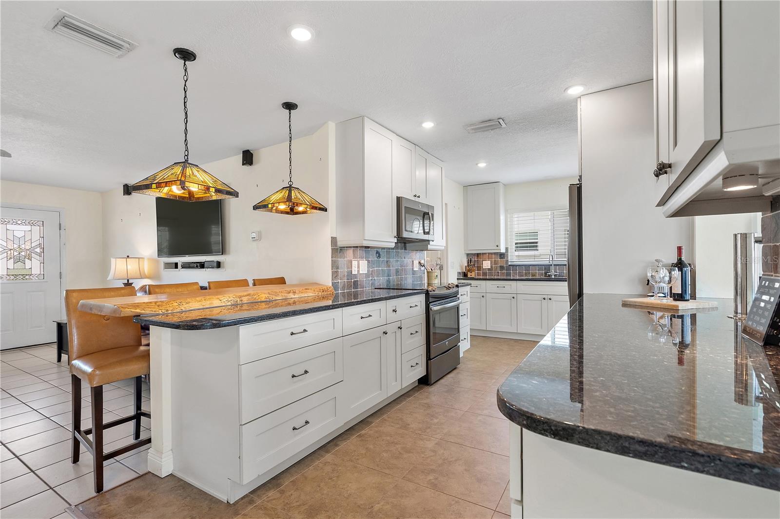 The contrast of the gleaming granite counters and the live-edge wood breakfast bar makes this kitchen stand out
