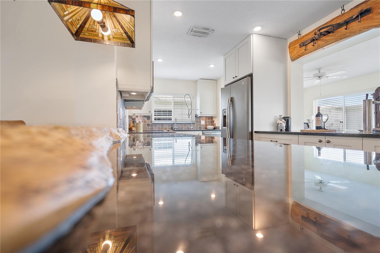 Pot rack matches the live-edge wood breakfast bar in this expansive kitchen