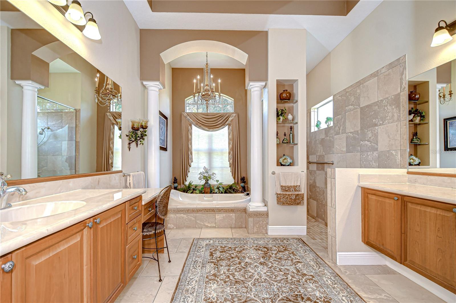 Primary Ensuite Bath, Separate Vanities (Make-Up Space), Deep Soaking Tub Flanked by Columns and Windows, Walk-in Tiled Shower, Built-in Shelving for Display or Towels