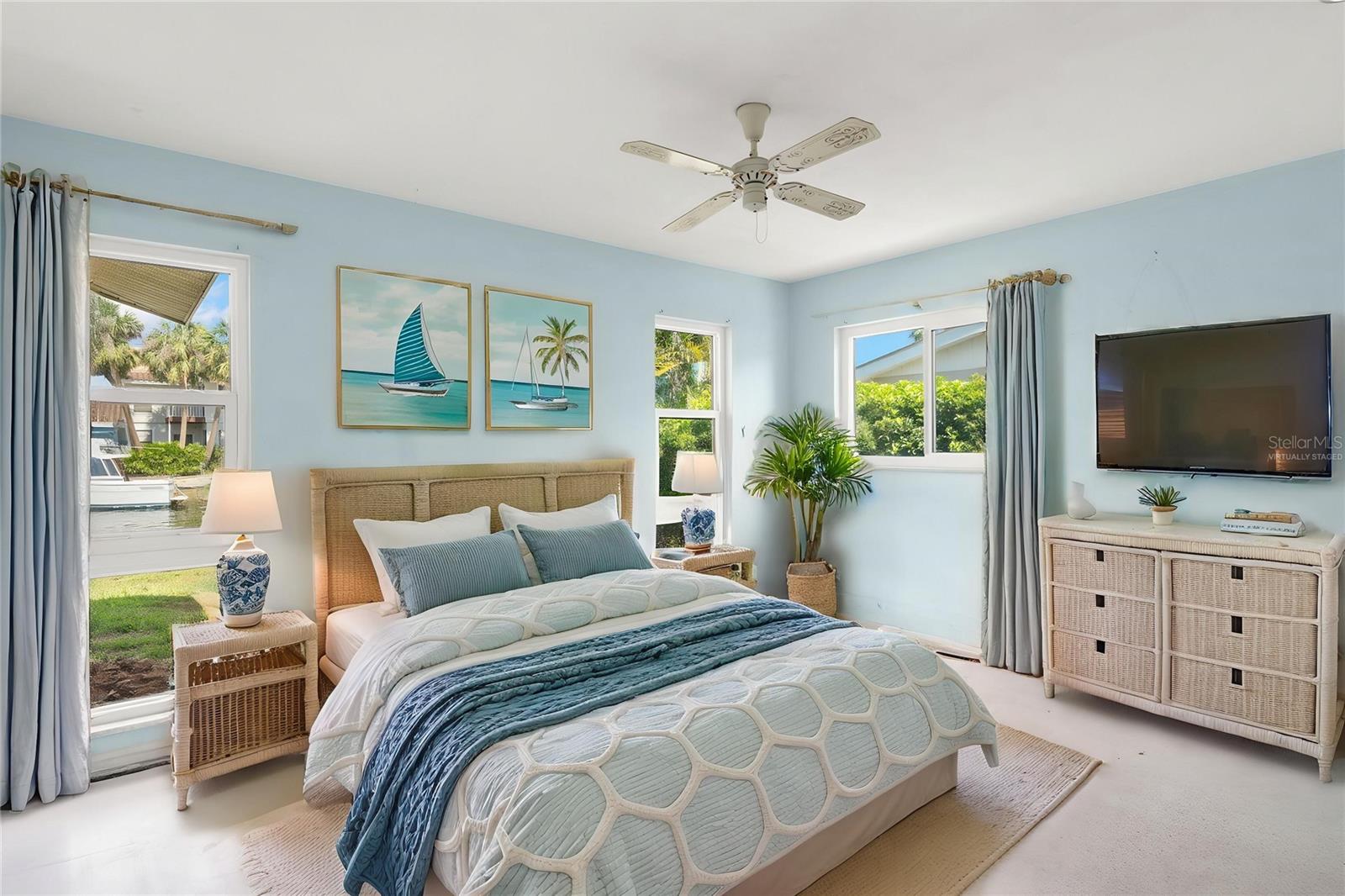 Guest room with windows providing views of the water. (Virtually Staged)