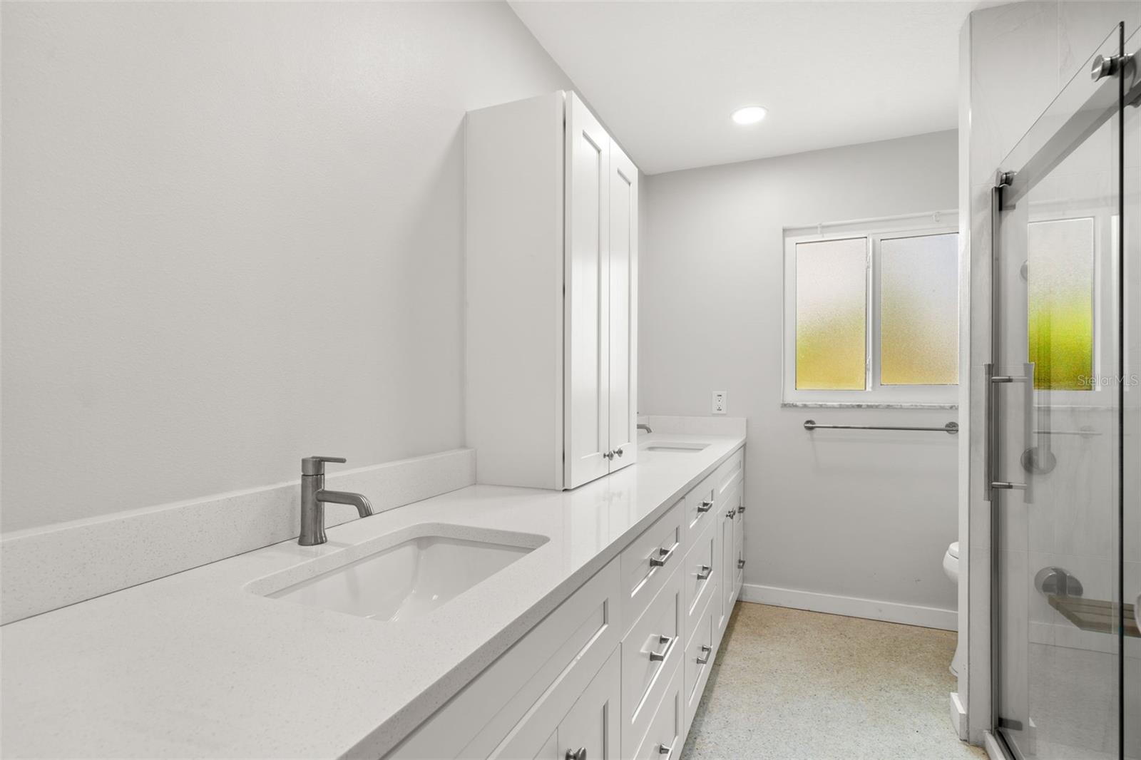 Guest Bath. Completely remodeled and updated in 2022, with walk-in shower, teak bench, white mission style cabinetry and dual sinks.