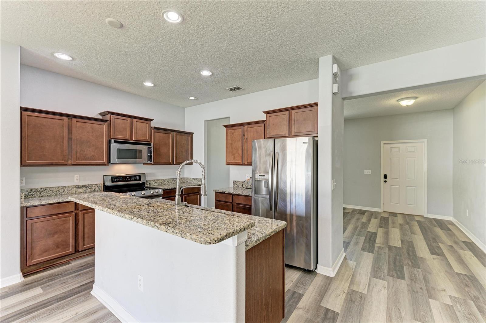 Kitchen with front door and dining area behind