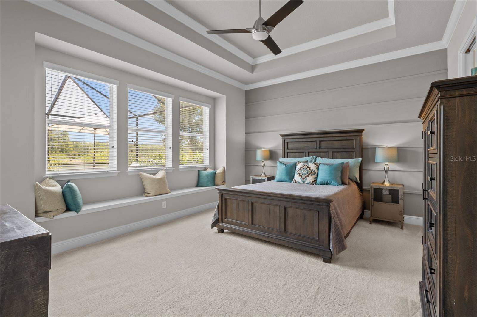 Primary Bedroom with Tray Ceiling, custom moldings, window seat, and view of pool + conservation