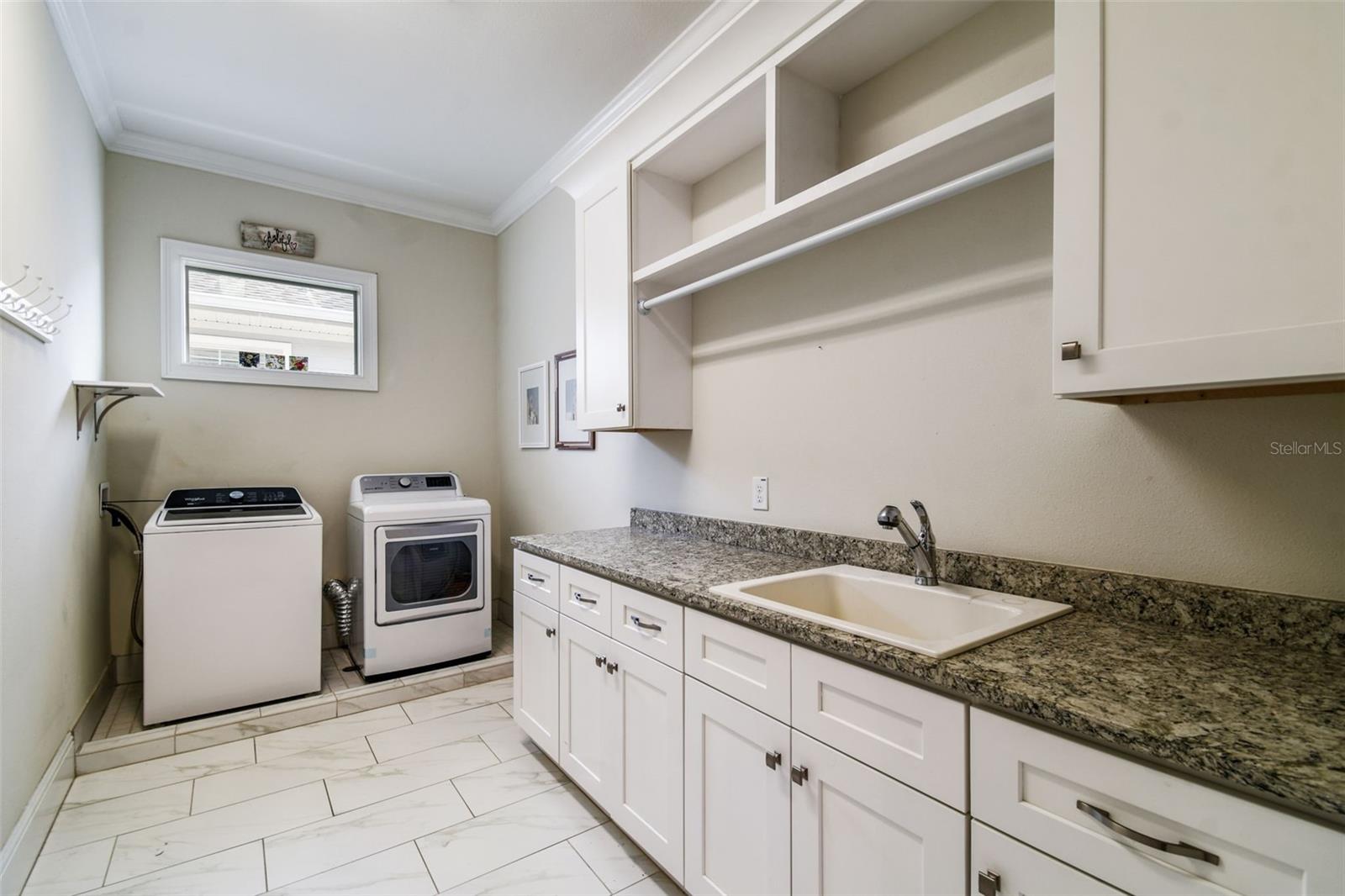 Spacious laundry room with built-in cabinetry and utility sink