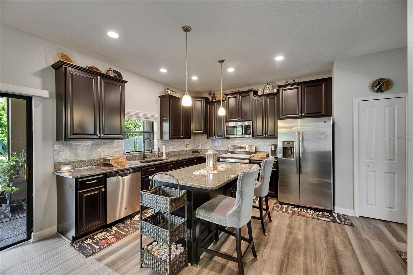 Staggered espresso maple cabinets are beautifully paired with granite countertops and a classic subway tile backsplash, creating a warm and sophisticated kitchen aesthetic.