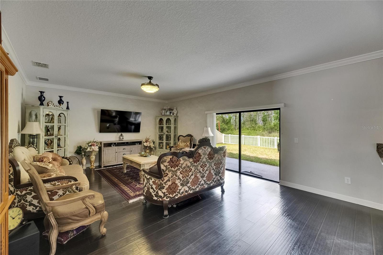 spacious family room features sliding glass doors leading to the backyard, ornate wood flooring, and unique ceiling fans—creating the perfect space for entertaining.