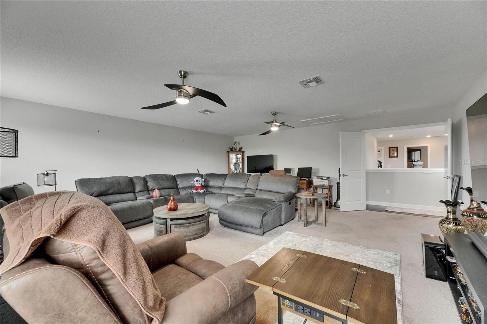 The media room is enclosed with elegant double French doors and enhanced by modern ceiling fans, creating a comfortable and stylish entertainment space.