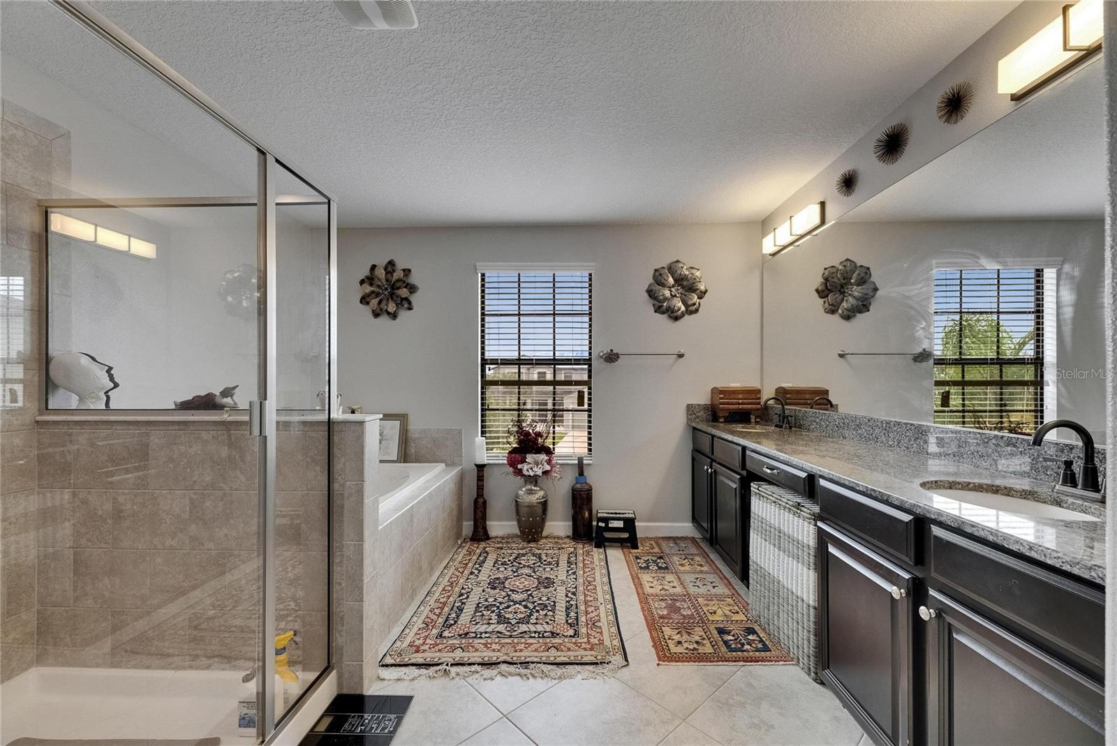 The well-designed master bath features dual sinks with granite countertops, modern LED lighting, and a layout that combines style with functionality.