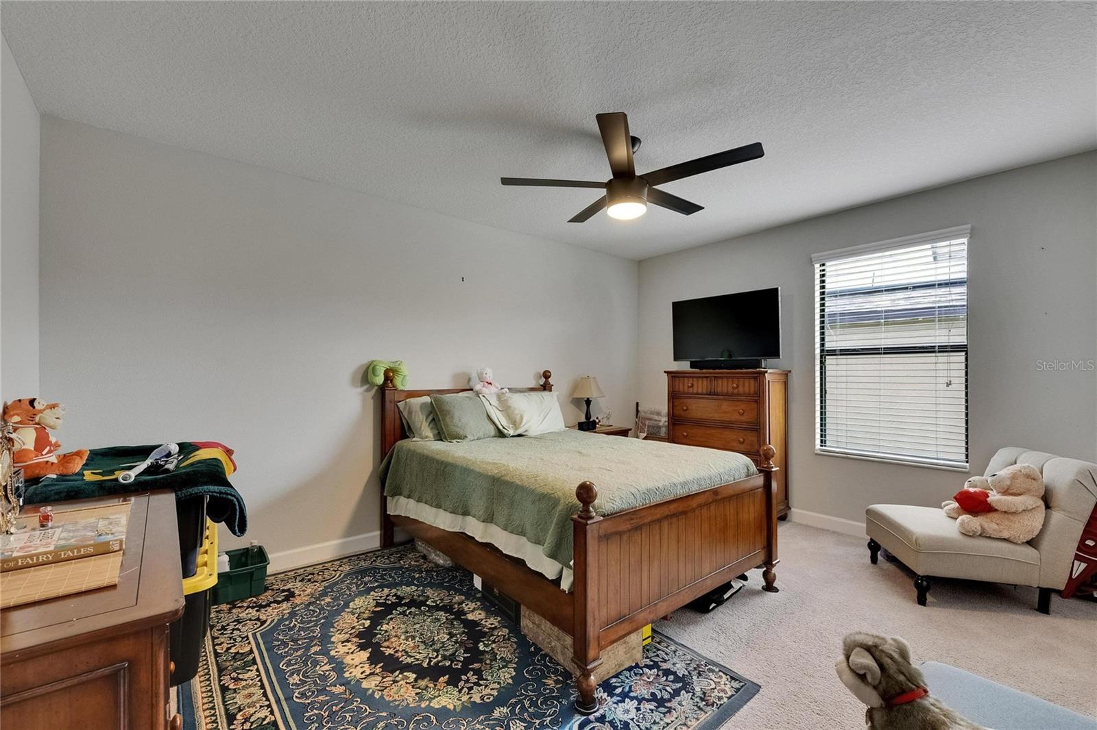 The oversized secondary bedroom offers plenty of space and comfort, complete with a ceiling fan to keep the room cool and inviting.