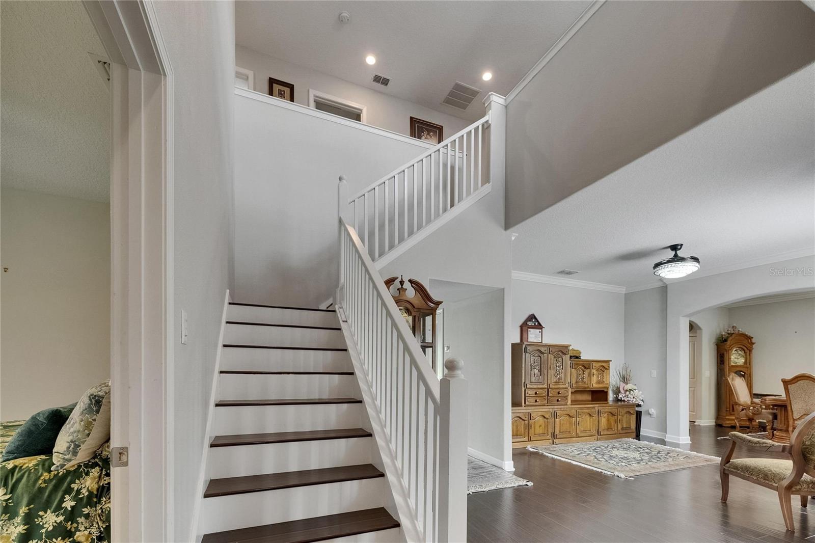 A grand wood staircase with elegant spindles adds a timeless touch to the foyer’s sophisticated design.