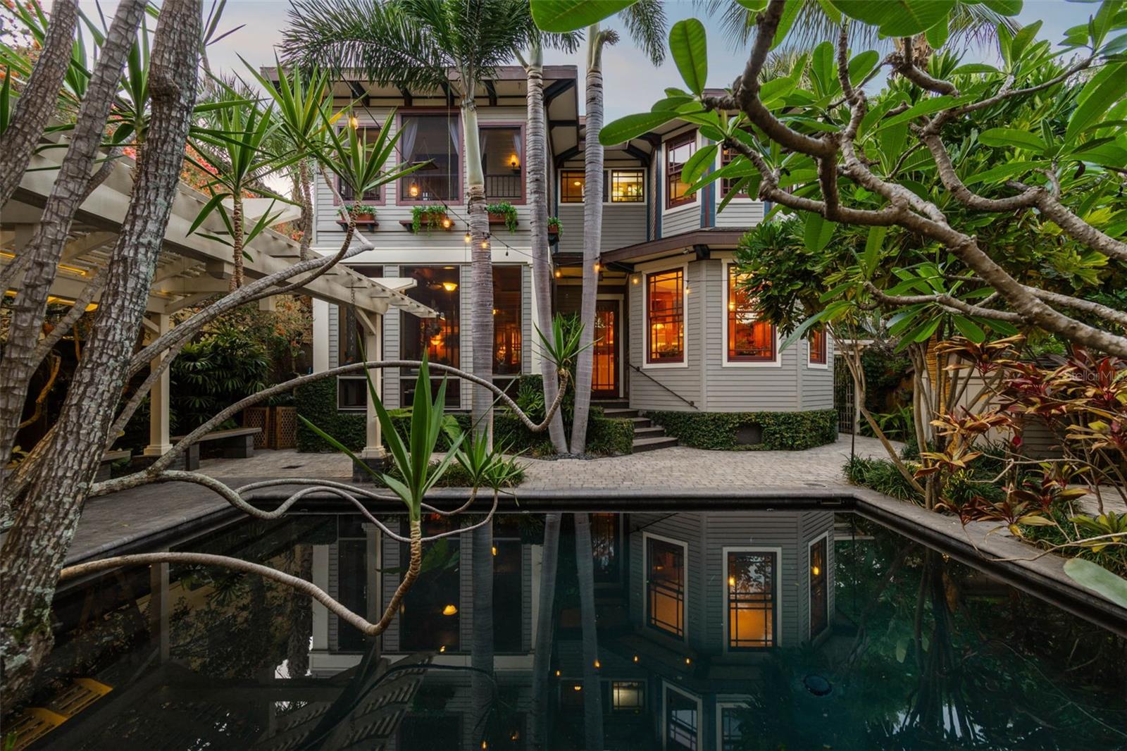 The idyllic dark-bottomed pool captures the reflections of the house and guesthouse