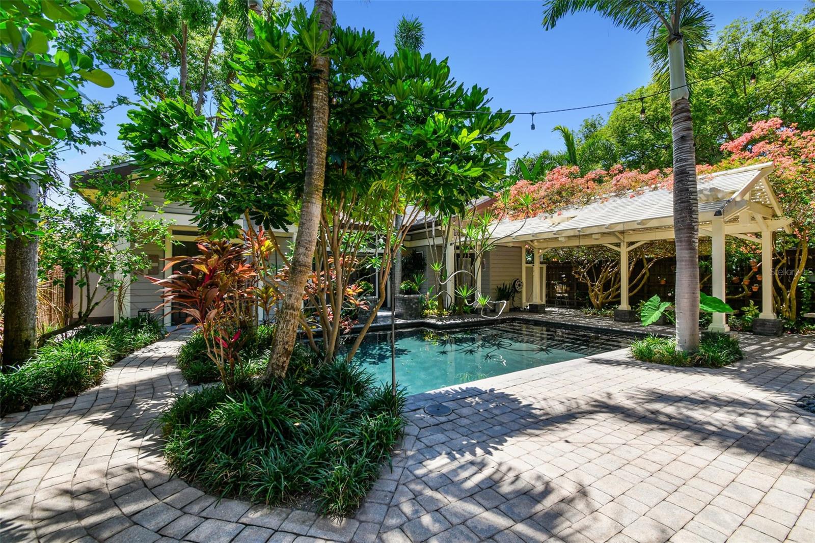 The backyard is a sanctuary where you will find a variety of exotic trees and plants, including unique Bromeliads throughout with Spineless Yuca and Frangipani reaching over the pool and blooming Bougainvilla atop the 20 foot pergola over the lanai.