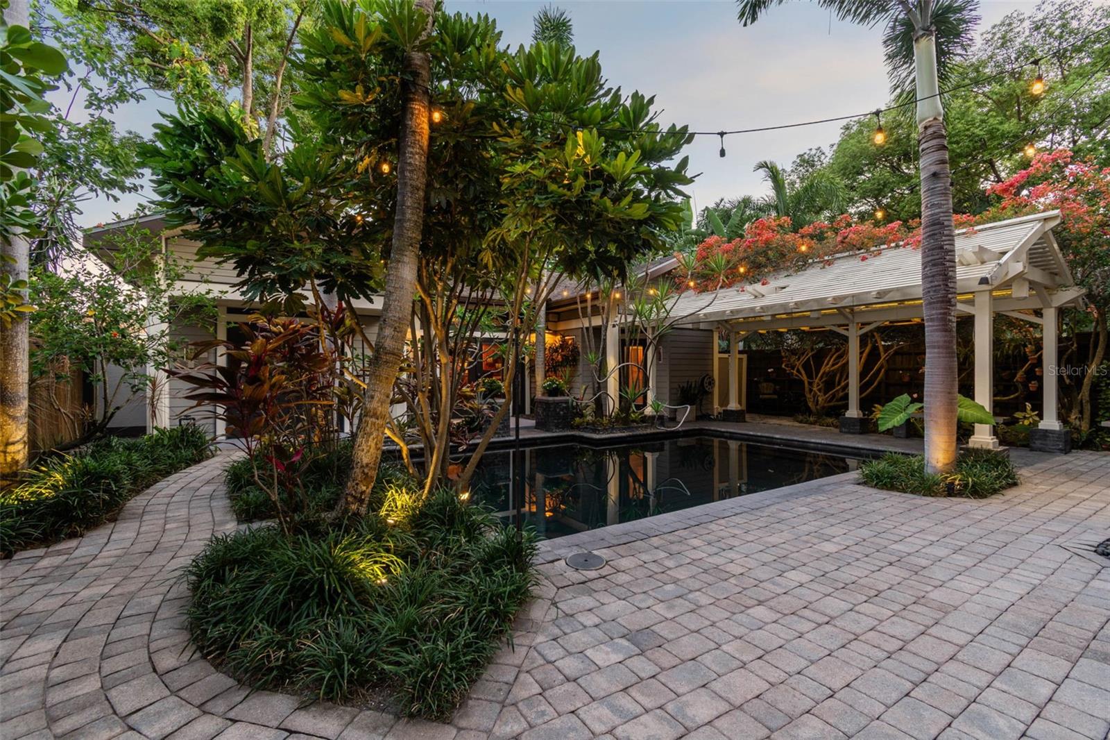 The idyllic dark-bottomed pool captures the reflections of the house and guesthouse