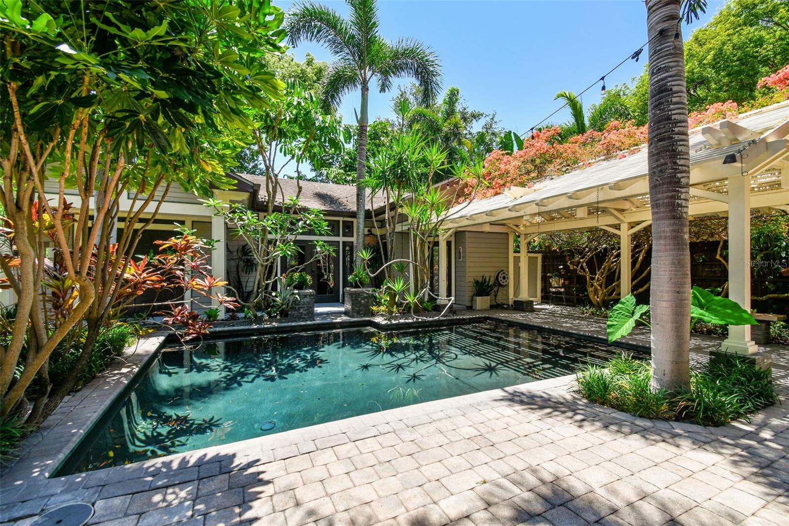The backyard is a sanctuary where you will find a variety of exotic trees and plants, including unique Bromeliads throughout with Spineless Yuca and Frangipani reaching over the pool and blooming Bougainvilla atop the 20 foot pergola over the lanai.
