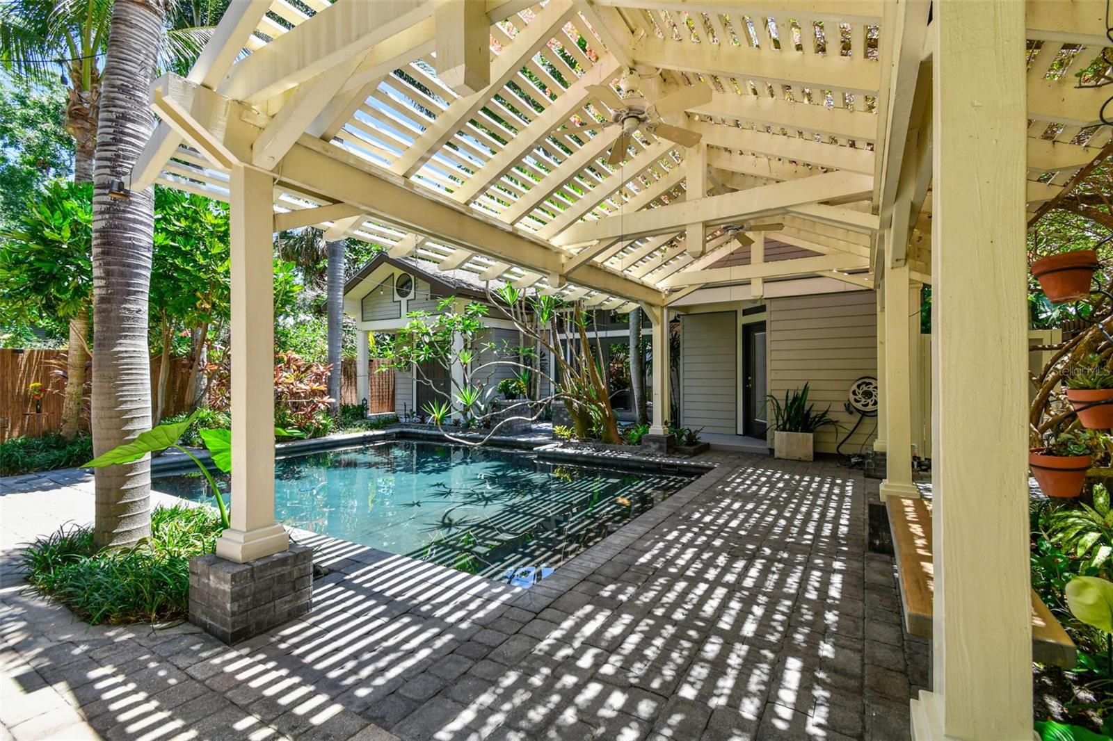 The backyard is a sanctuary where you will find a variety of exotic trees and plants, including unique Bromeliads throughout with Spineless Yuca and Frangipani reaching over the pool and blooming Bougainvilla atop the 20 foot pergola over the lanai.