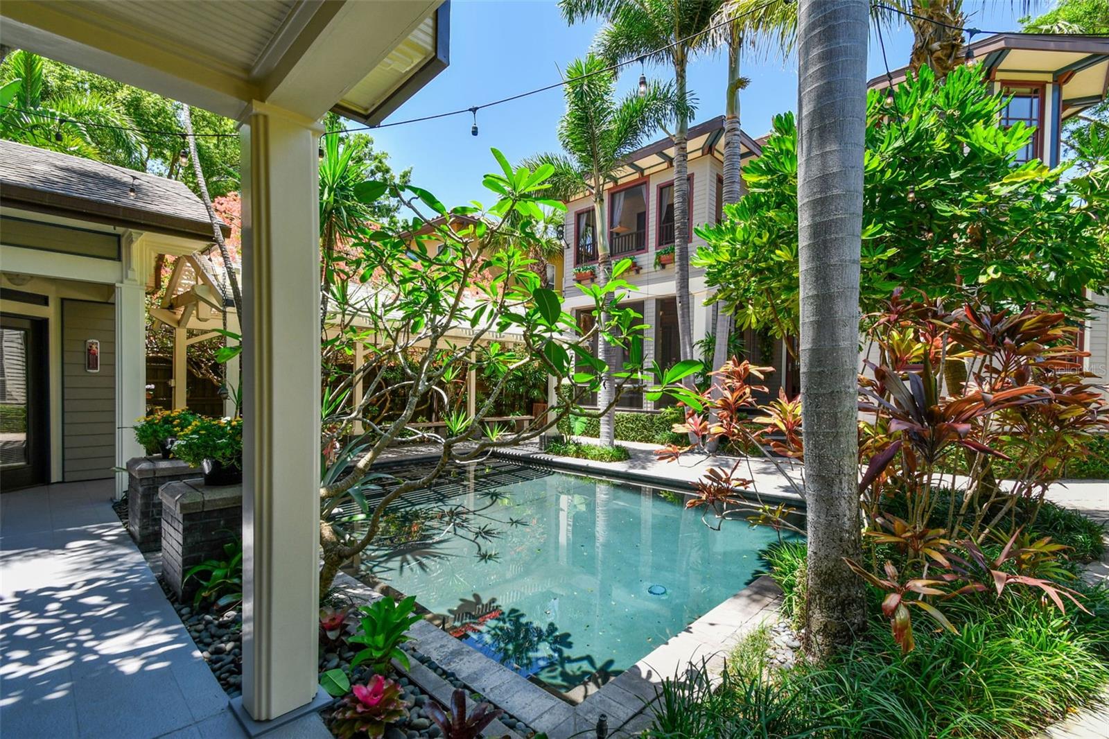 The backyard is a sanctuary where you will find a variety of exotic trees and plants, including unique Bromeliads throughout with Spineless Yuca and Frangipani reaching over the pool and blooming Bougainvilla atop the 20 foot pergola over the lanai.