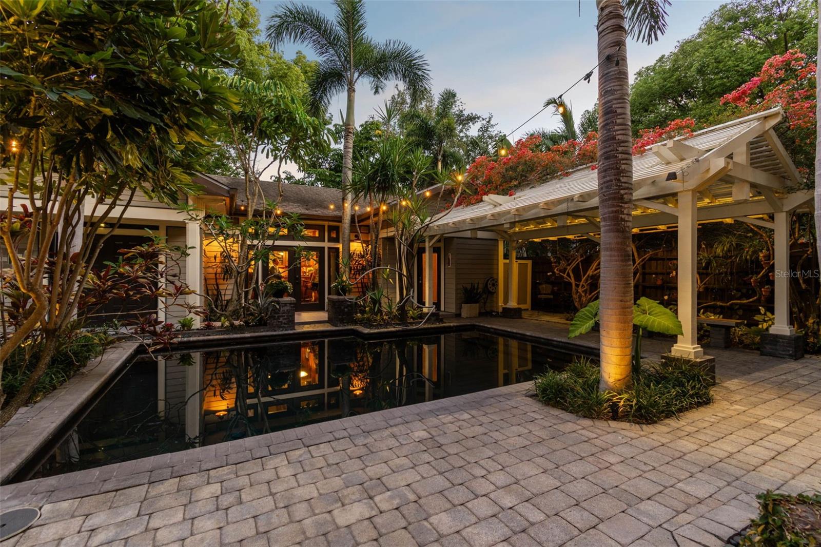The idyllic dark-bottomed pool captures the reflections of the house and guesthouse