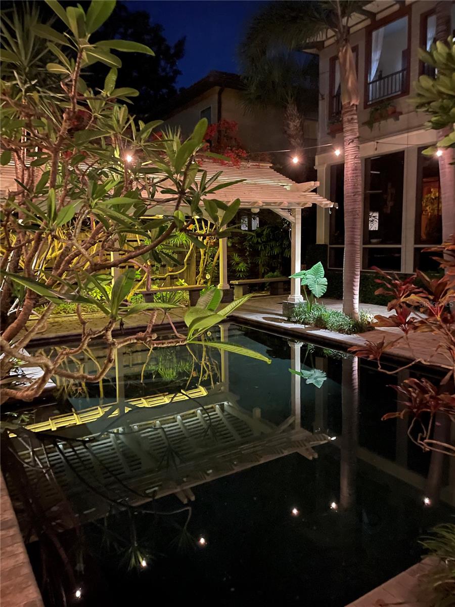 The idyllic dark-bottomed pool captures the reflections of the house and guesthouse