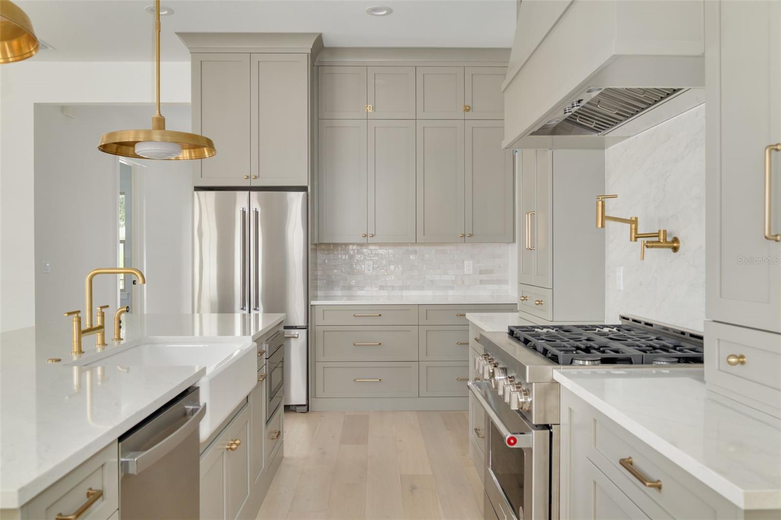 Upgraded Calcutta Marble and Soapstone countertops surrounding a Kohler Farmhouse Sink and stylish brass accents. This photo is a different model, similar finishes will be provided