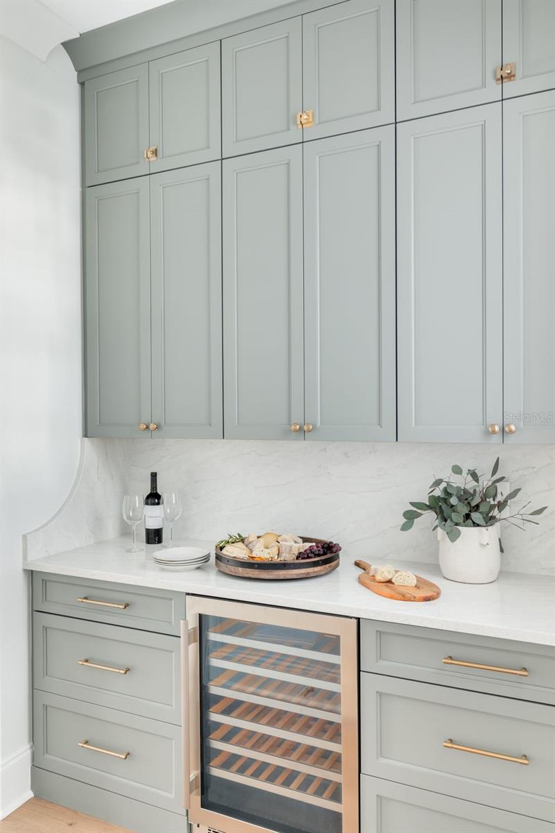 The Butler's pantry with wine refrigerator connects the kitchen and dining room. This photo is a different model, similar finishes will be provided.