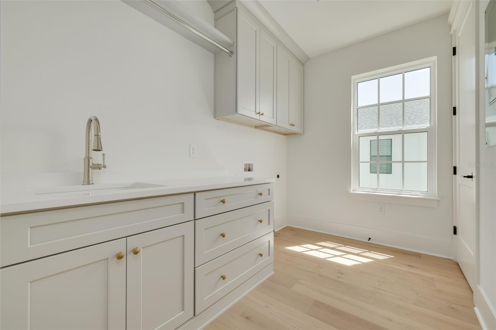 Laundry room on the second level includes utility sink and built-in storage. This photo is a different model, similar finishes will be provided.
