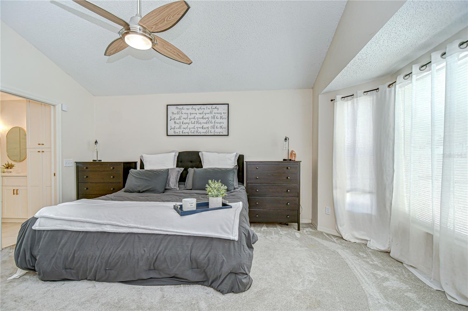 The primary suite tucked at the back of the home featuring pool views through a bay window and new carpet!