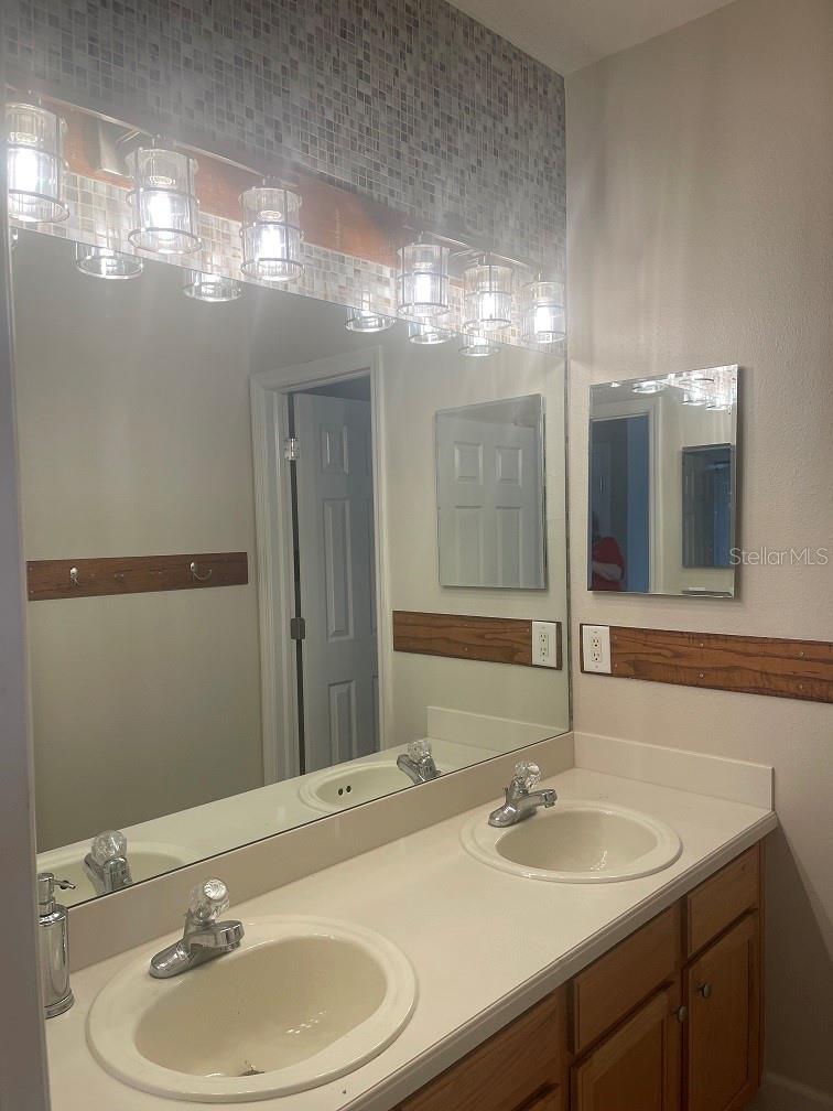 Upstairs hall bath with two sinks and a door leading to the tub and commode