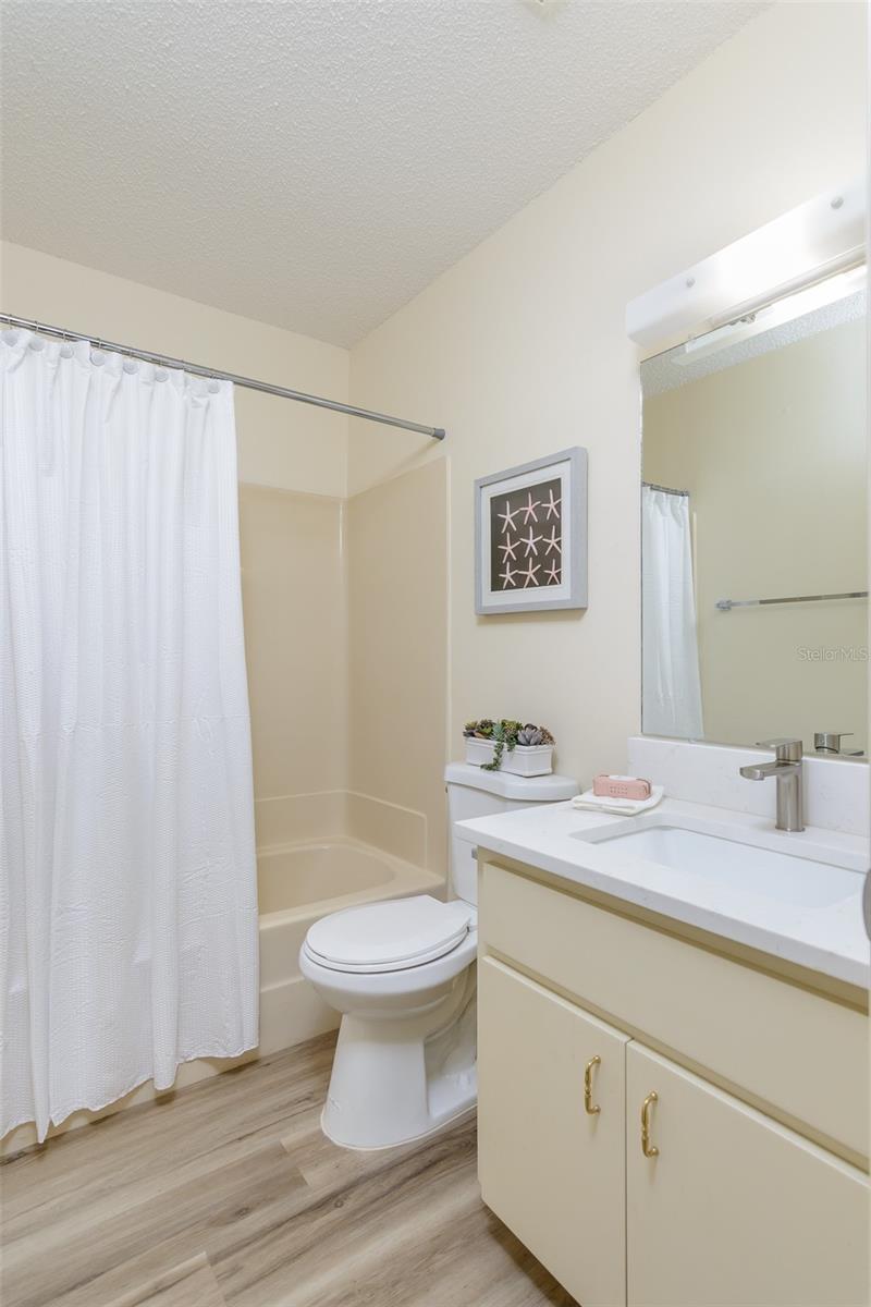 Guest bathroom adjacent to guest bedroom with tub shower, new countertop, and new undermount sink.